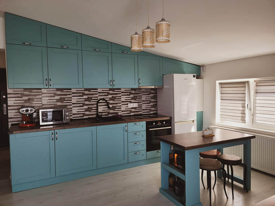 Bucatarie la comanda  cu insula, intr-un apartament la mansarda, pe o culoare verde deschis